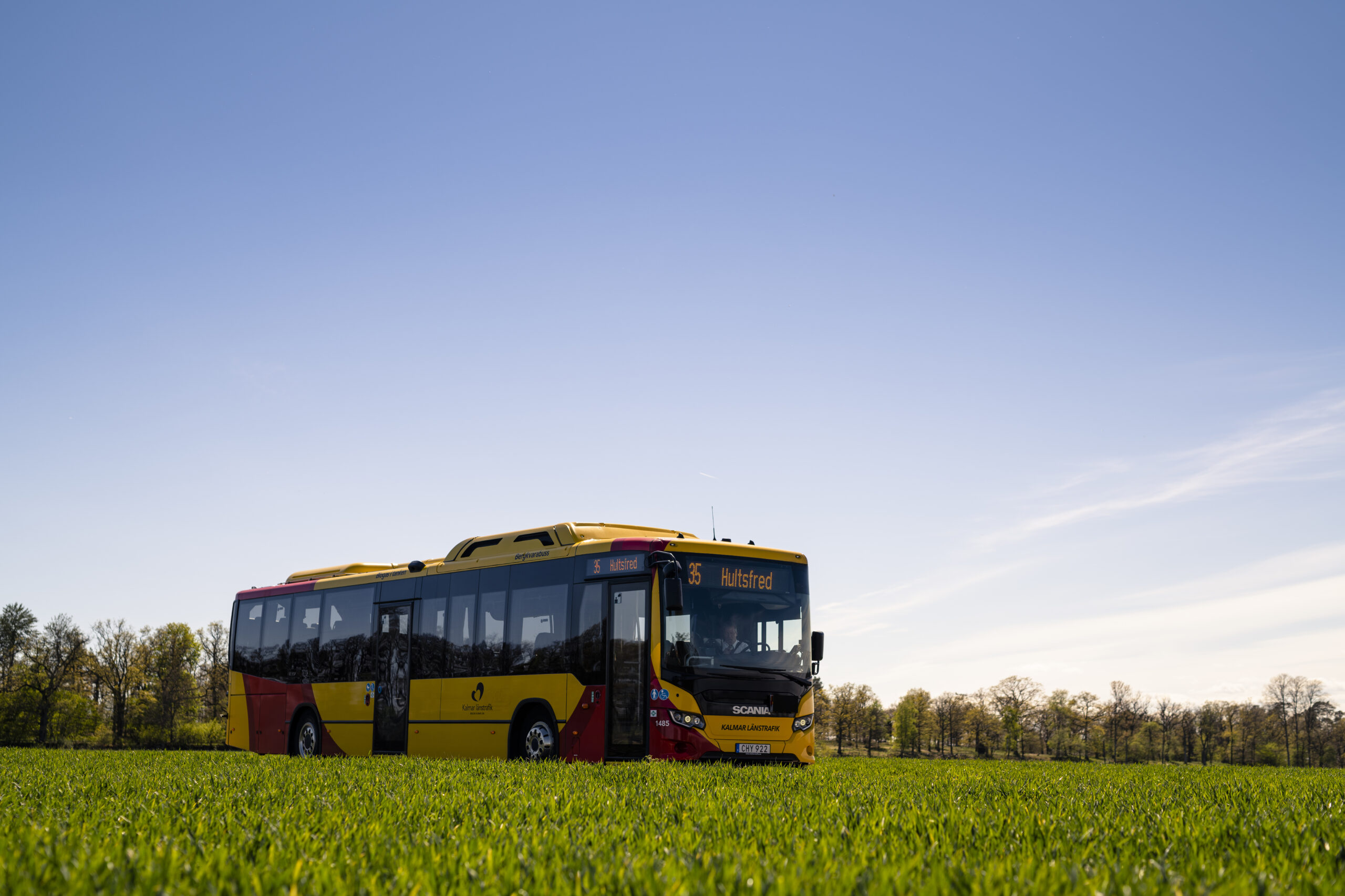 Genrebild. Utsikt mot en buss om kör på en väg längs med en åker.