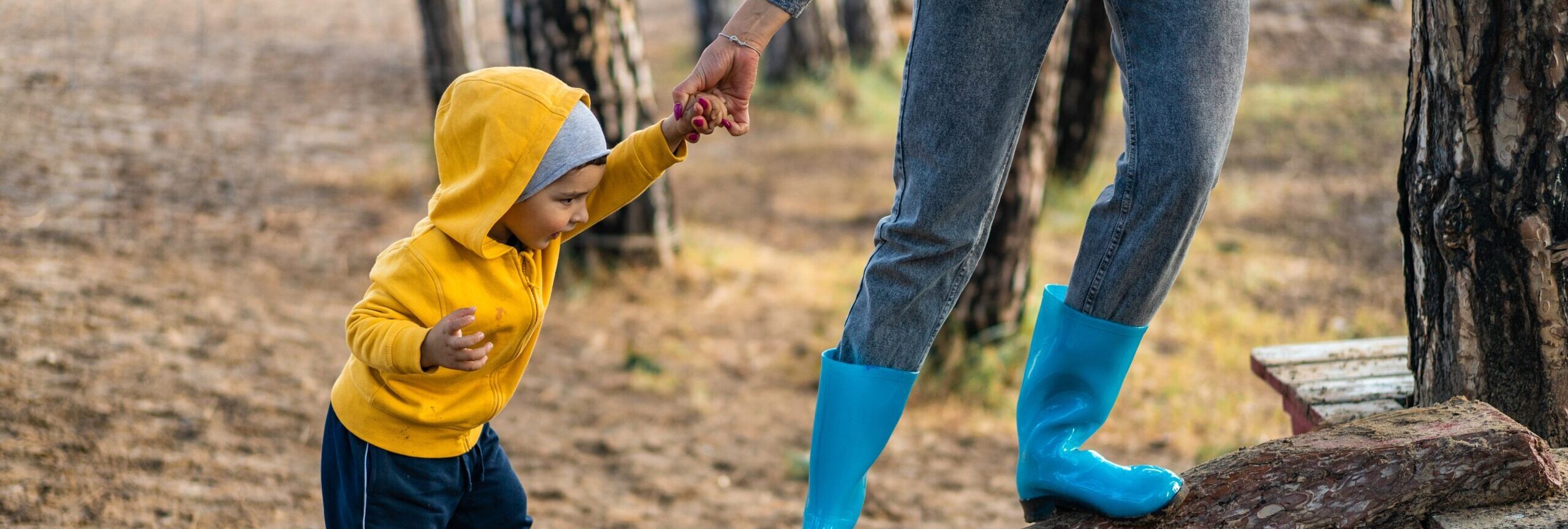 Ett barn går på en stock och håller en vuxen i handen