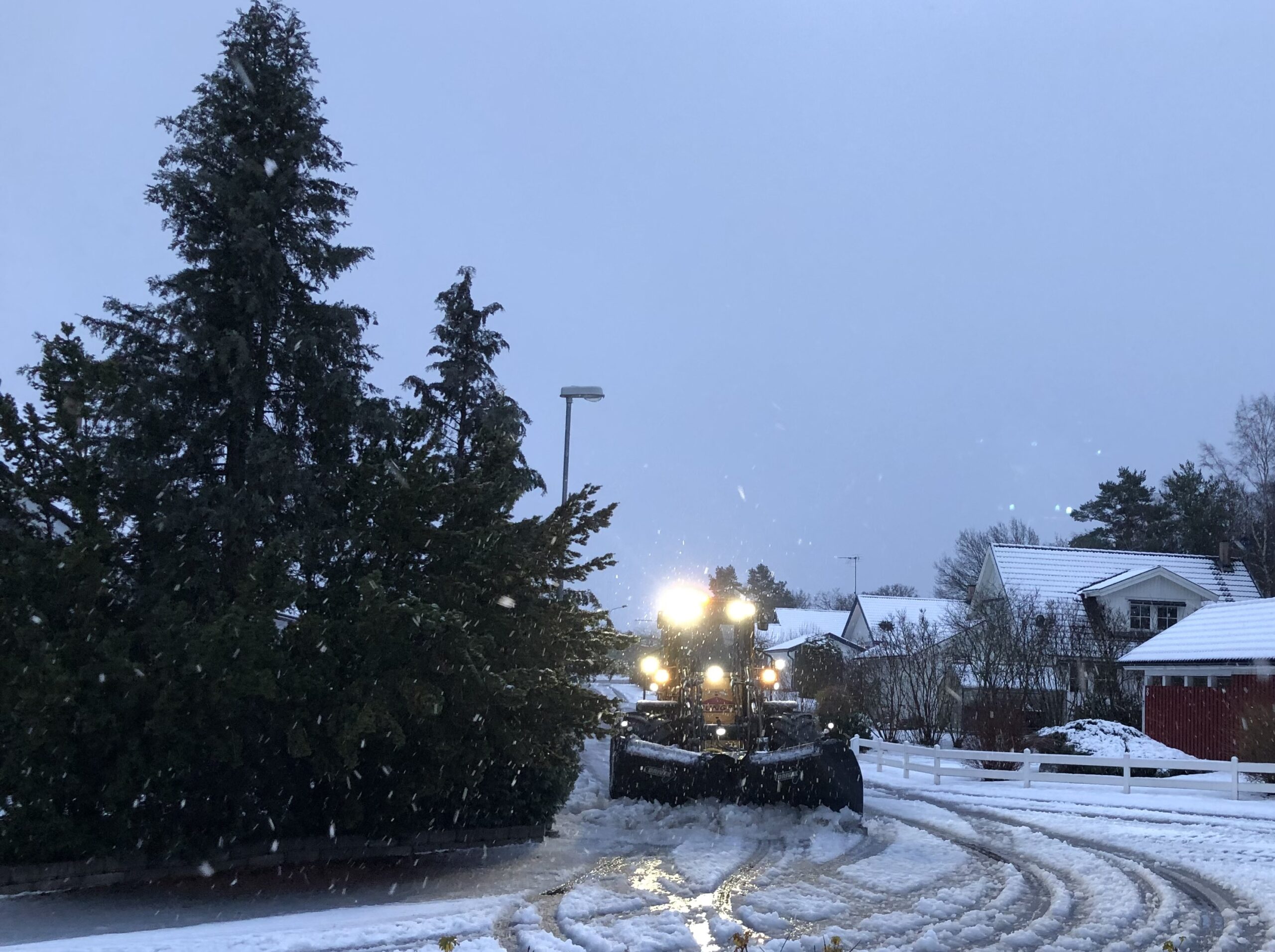 En plogbil röjer undan snö på i ett bostadsområde.