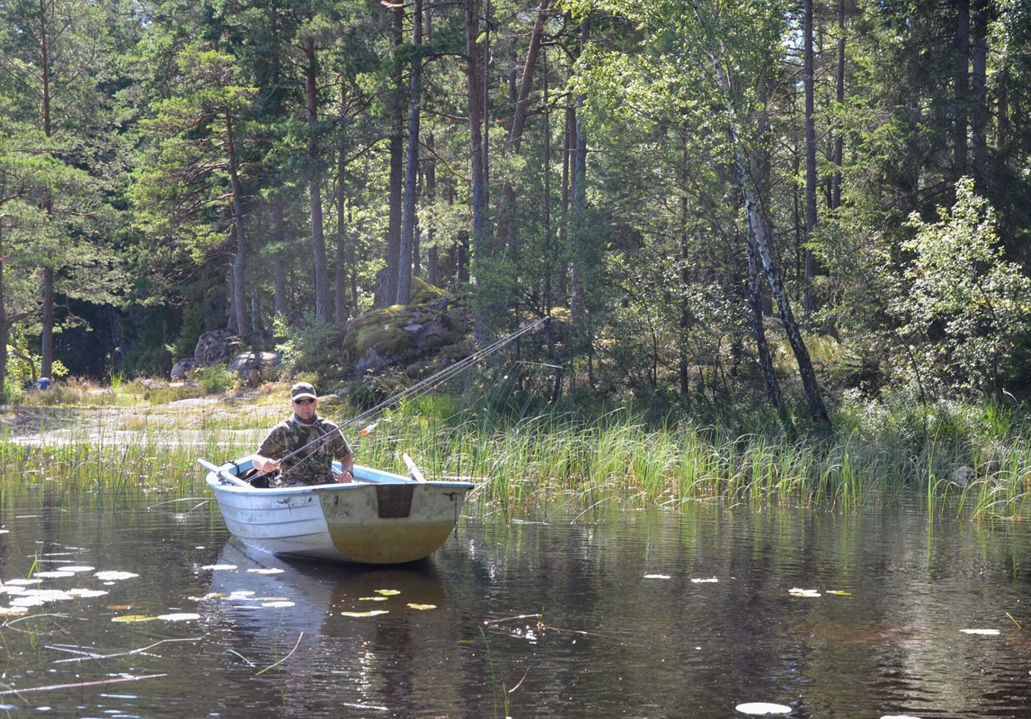 En fiskare i en liten roddbåt i en insjö med näckrosor