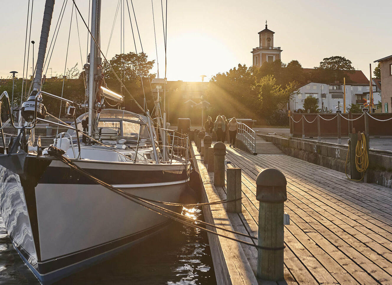 Segelbåt i solnedgång i en gästhamn vid en träbrygga