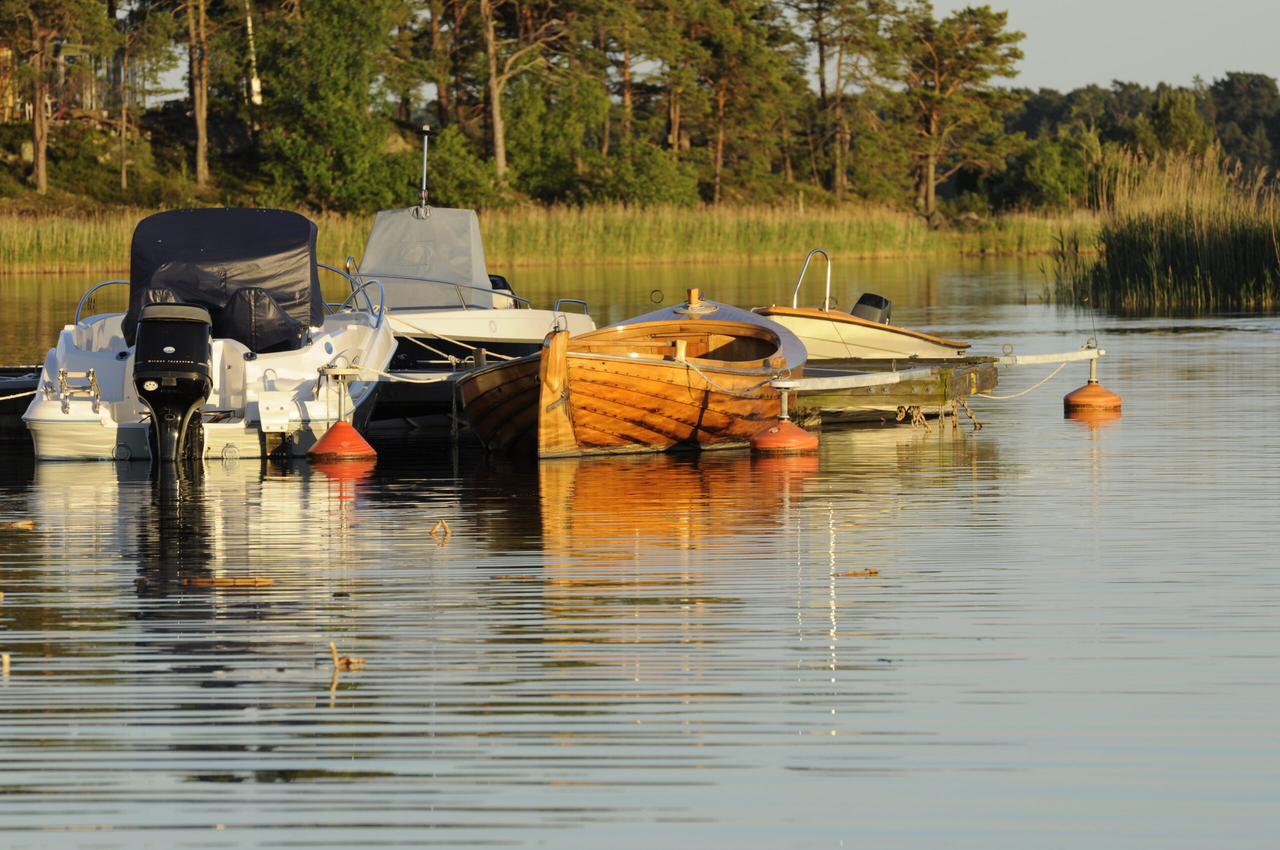 Två båtar ligger förtöjda vid en brygga. Det är sommar och solen är på väg ner.