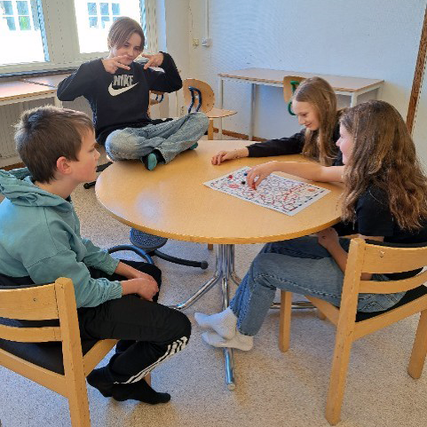 Elever sitter i ett grupprum i skolan och spelar ett brädspel.