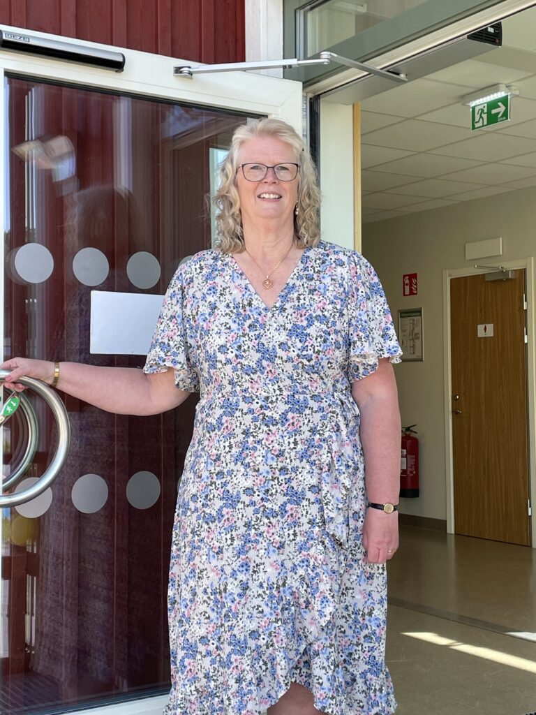 Foto. Rektor Anita håller upp dörren till Fliserydskolan.