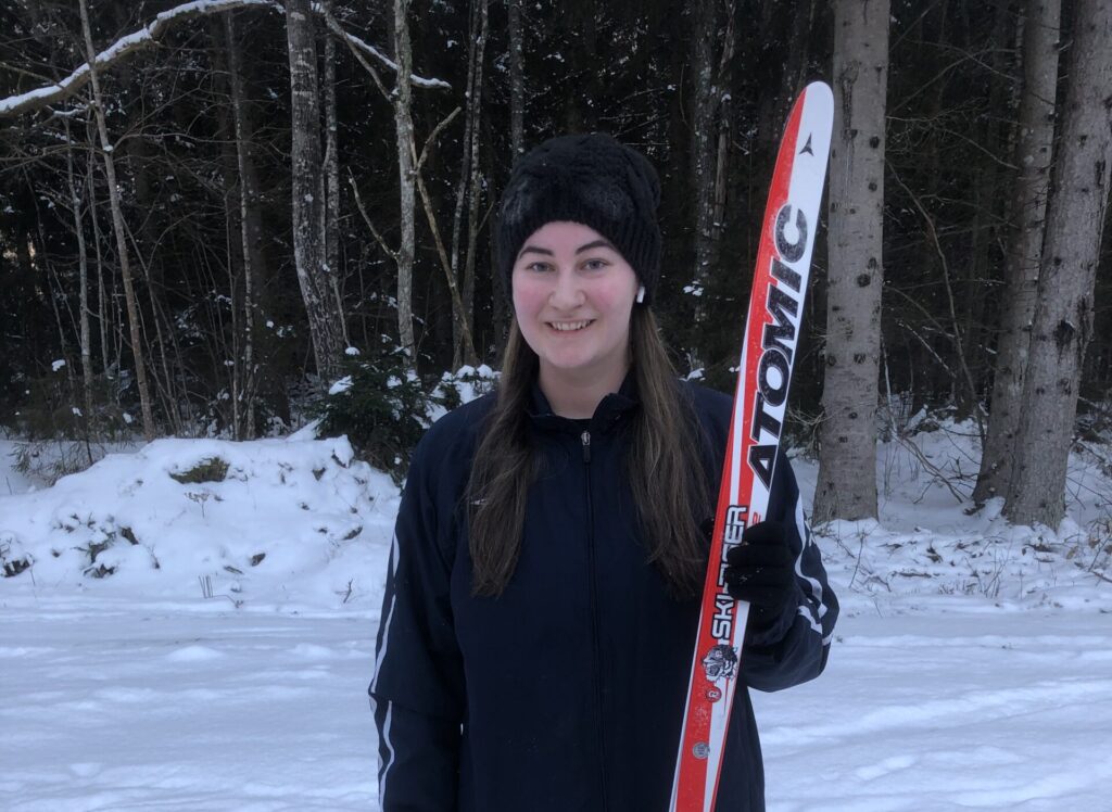 Kvinna står med ett par längdskidor. Ålems OK.