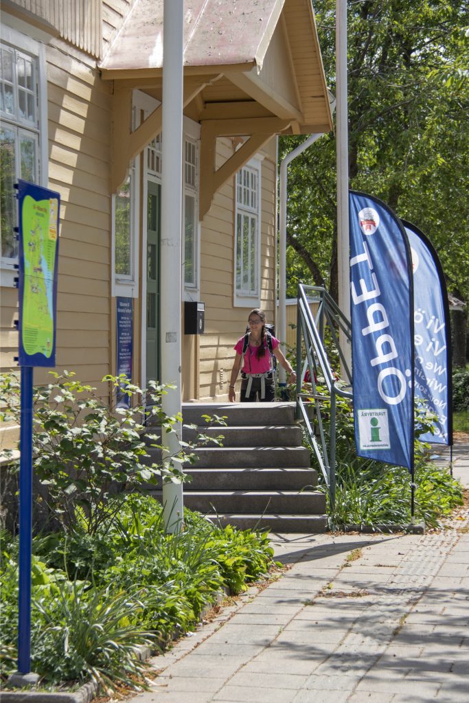 Person går upp för trappan till en gul byggnad